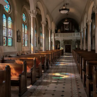 Sunlit Chapel Pews With Stained Glass