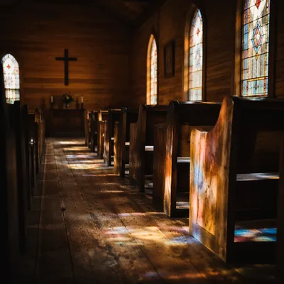 Sunlit Chapel Pews with Stained Glass