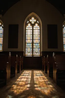 Sunlit Chapel Pews with Stained Glass