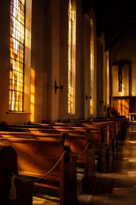 Sunlit Stained Glass Over Empty Church Pews