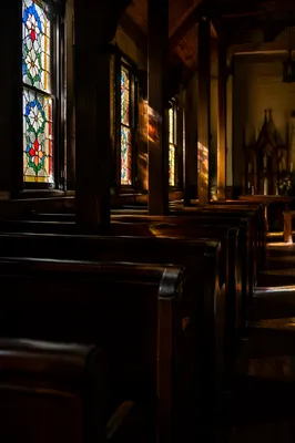 Sunlit Chapel Pews with Stained Glass