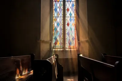 Sunlit Chapel Pews and Stained Glass