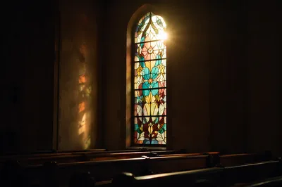 Sunlit Stained Glass Above Chapel Pews