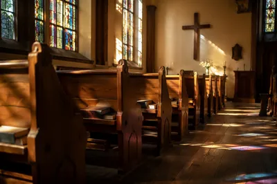 Sunlit Chapel Pews with Stained Glass