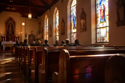 Sunlit Chapel Pews with Stained Glass