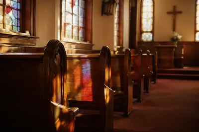 Sunlit Wooden Chapel Pews with Stained Glass