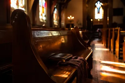 Sunlit Chapel Pews with Stained Glass