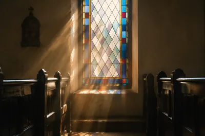 Sunlit Chapel Pews and Stained Glass