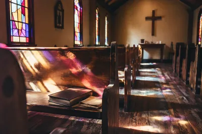 Sunlit Chapel Pews With Stained Glass