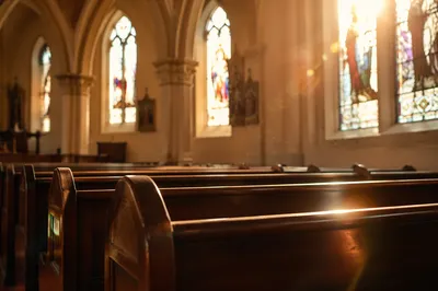 Sunlit Church Pews With Stained Glass
