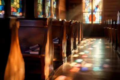 Sunlit Chapel Pews with Stained Glass