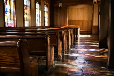 Sunlit Chapel Pews with Stained Glass