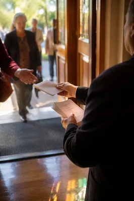 Church Usher Welcoming Guests with Bulletins