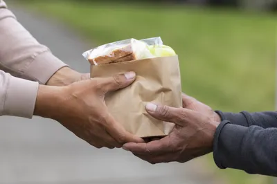 Hands Sharing Meal Bag in Outreach Ministry