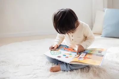 Child Reading Picture Book on Rug