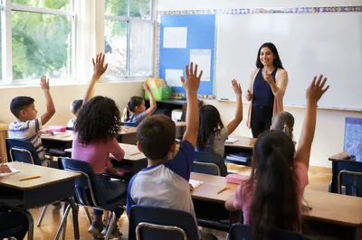 Children Raising Hands in Bright Classroom