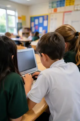 Elementary Students Collaborating Around Classroom Laptop