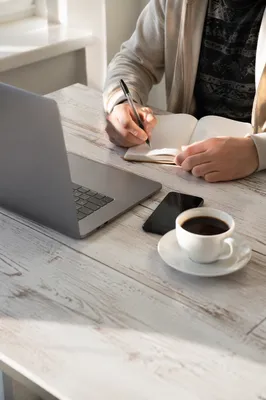 Focused Student Writing Notes at Laptop