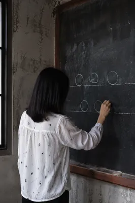 Teacher Writing on Blackboard in Classroom