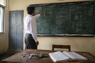 Teacher Explaining Lessons at Chalkboard