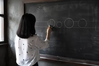 Teacher Writing on Classroom Chalkboard