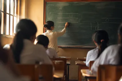 Teacher Writing on Classroom Chalkboard