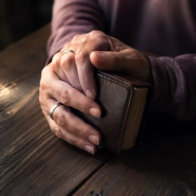 Anxious Hands Holding Bible in Warm Light