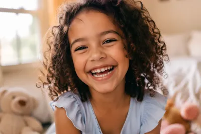 Giggling Child in Sunlit Bedroom Portrait