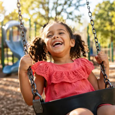 Laughing Little Girl on Playground Swing