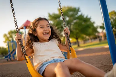 Laughing Girl on Playground Swing