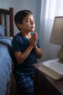 Young Boy Praying Beside Bed