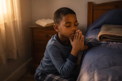 Young Boy Praying Beside Bed at Dawn