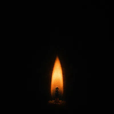 Single Candle Flame in Vast Darkness