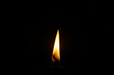 Single Candle Flame in Vast Darkness