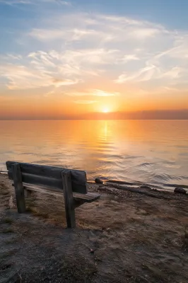 Sunrise Over Calm Ocean with Bench