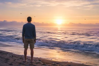 Lone Figure Watching Sunrise Over Ocean