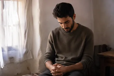 Young Man Bowed in Gentle Window Light