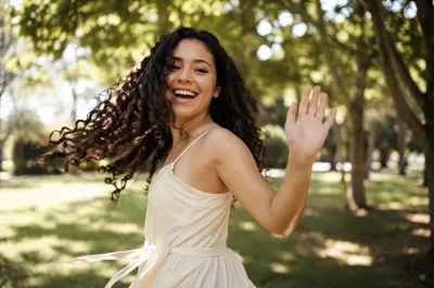 Joyful Woman Twirling Under Sunlit Trees