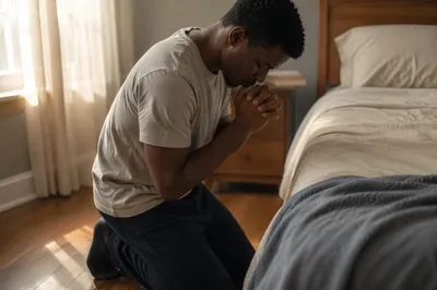 Young Man Praying Beside Bed