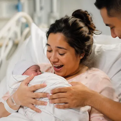 Joyful Mother Holding Newborn in Hospital
