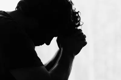 Overwhelmed Person in Prayerful Silhouette