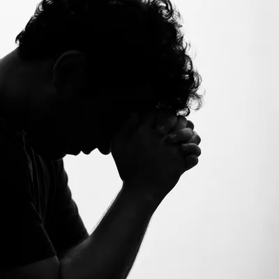 Silhouette of Overwhelmed Person in Prayer