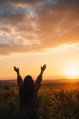 Silhouetted Figure with Raised Hands at Sunset