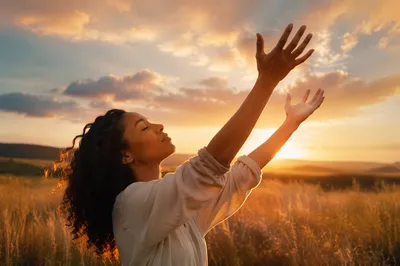 Young Woman with Hands Raised at Sunset