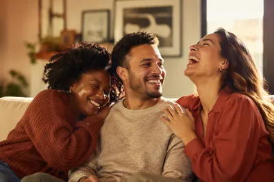 Three Adult Siblings Laughing on Sofa