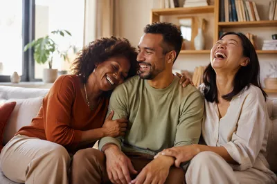 Three Adult Siblings Laughing on Sofa