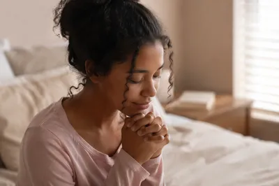 Teen Girl Praying by Bedroom Window