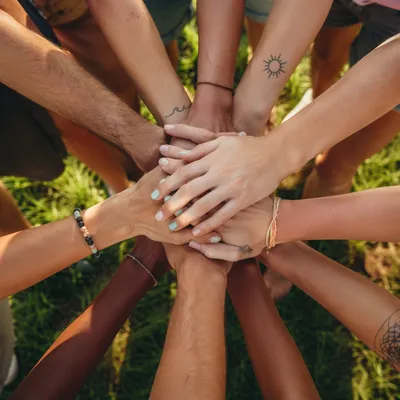 Diverse Hands Stacked in Unity on Grass