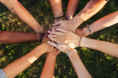 Diverse Hands Stacked in Unity on Grass