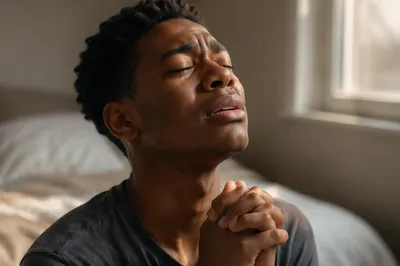 Emotional Young Man Praying in Bedroom